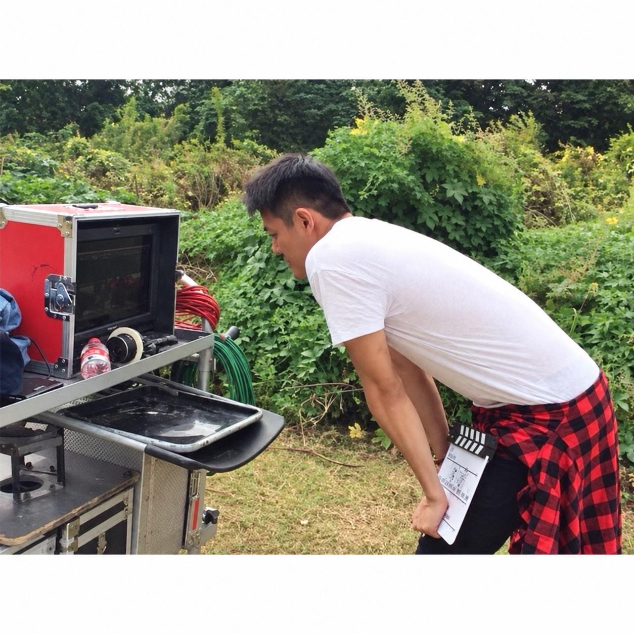 Stanley Yang reviewing a production monitor on an outdoor film set