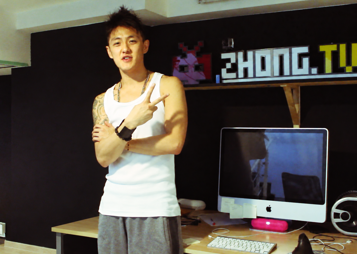 Stanley Yang in the Zhong.TV studio beside the wall sign
